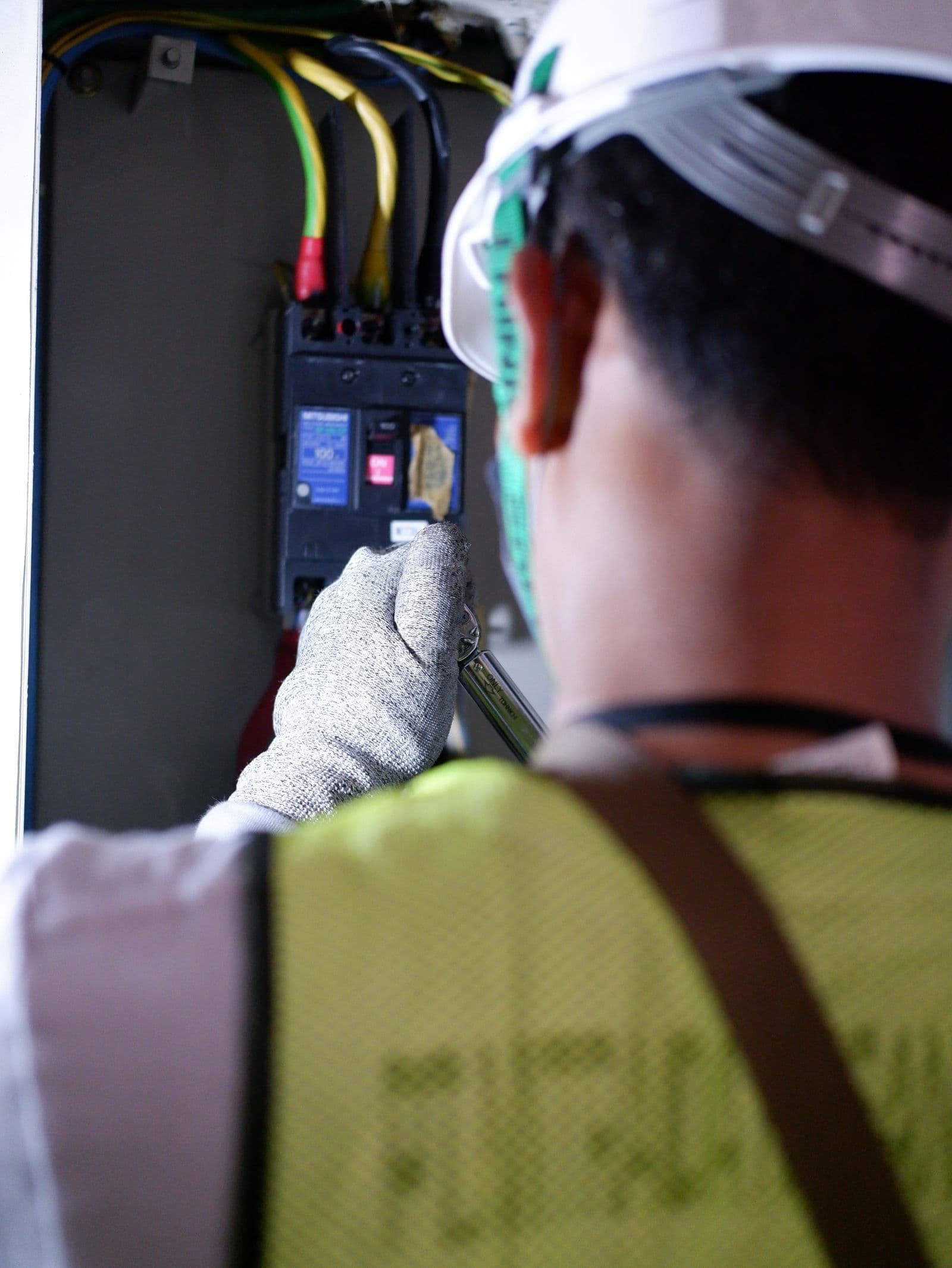 Electrician wearing gloves working safely on a circuit breaker box