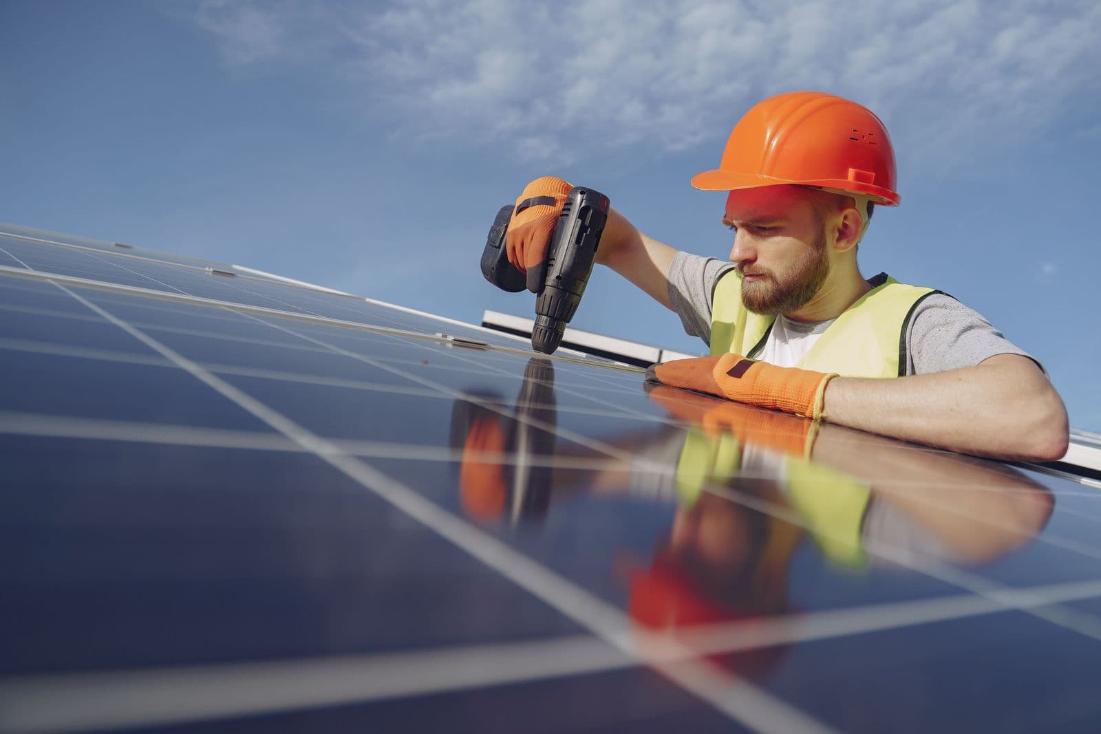 Electrician installing a solar photovoltaic panel with a drill